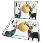 Description: Add a touch of modern elegance to your serving table with this luxurious set of serving trays. These trays feature a distinctive geometric deer design with intricate, intertwined shapes and shiny golden accents, creating an eye-catching piece that enhances any space. Suitable for serving or as decor in the living room, these trays add a unique charm to any home. Specifications: Material: High-quality, durable transparent glass with golden metallic accents Quantity: Set of 2 in different sizes Dimensions: Large Tray: 45 × 30 cm Small Tray: 35 × 25 cm Design: Colorful geometric deer patterns with gold detailing Usage: For serving or as a chic decorative piece Durability: Glass layer protects the design, ensuring colors remain vibrant over time Features: Contemporary design complements various interior styles Ideal for serving coffee, tea, snacks, or as a decorative tray Easy to clean; simply wipe with a damp cloth Side handles for easy carrying and use Ideal Usage: Use these trays to serve drinks and snacks to guests or place them as an elegant decorative piece on the coffee table or buffet. Their sophisticated design makes them a perfect choice for adding an artistic touch to modern homes.